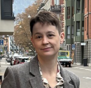 Marlowe, a white nonbinary person with short brown hair, wearing a tweed jacket.